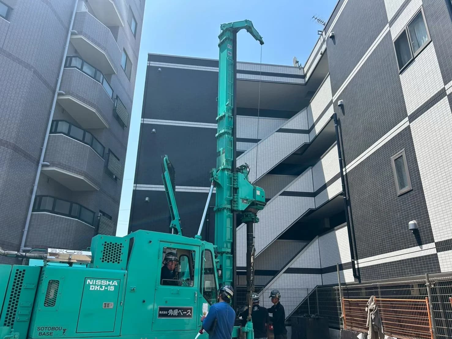 周囲を建物に囲まれた敷地で稼働する杭施工機